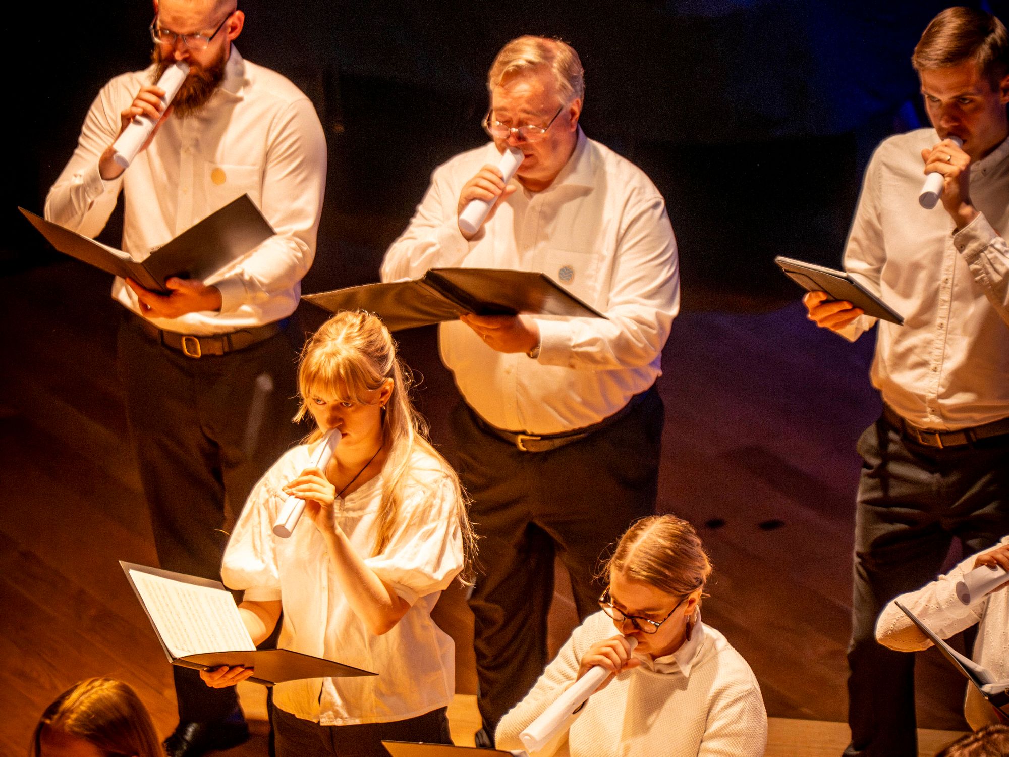 Kuorolaiset laulavat paperirullat suullaan © Tuomas Tenkanen