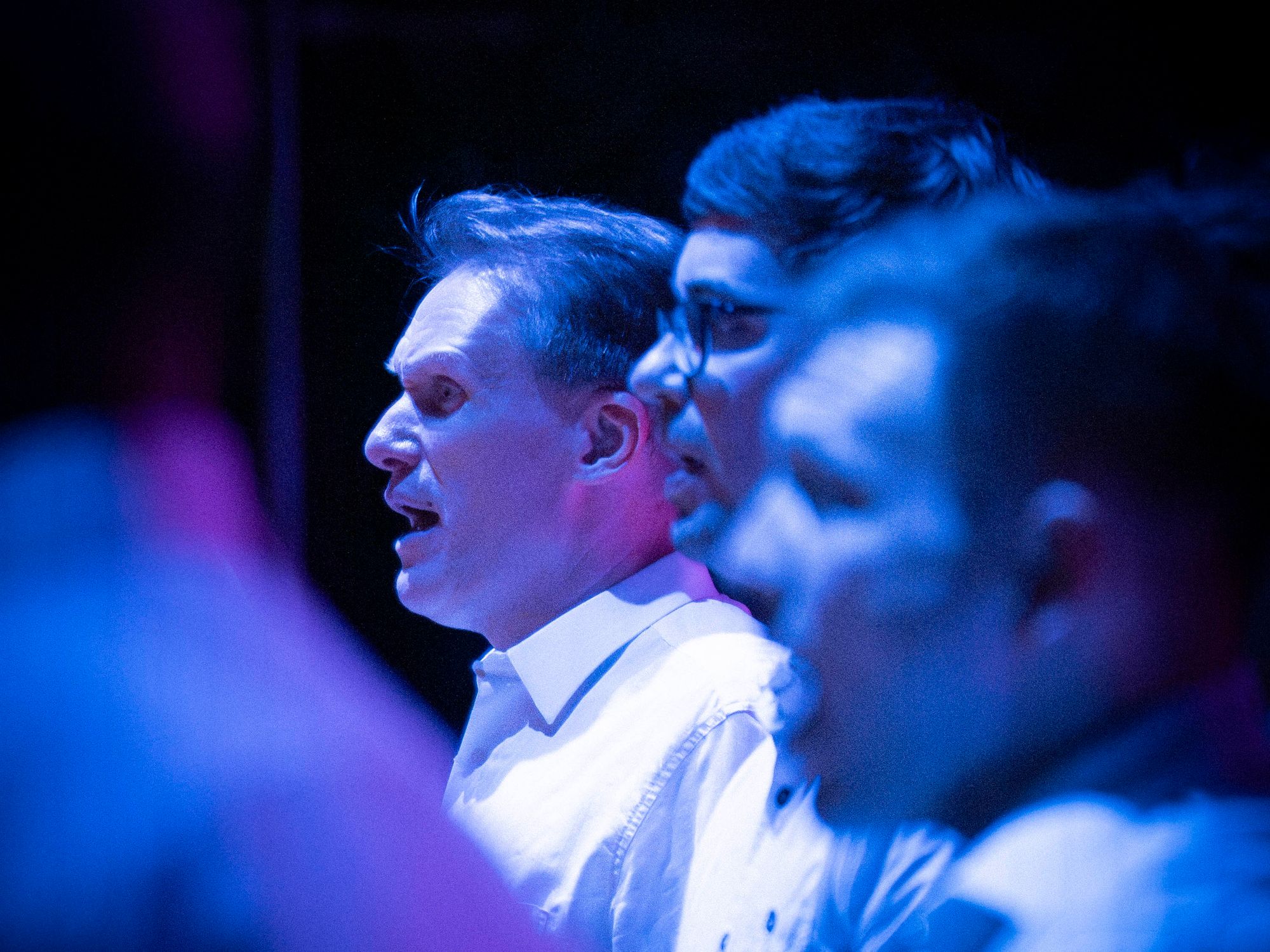 Mieslaulajia esiintymässä sinisen valon hehkussa © Tuomas Tenkanen